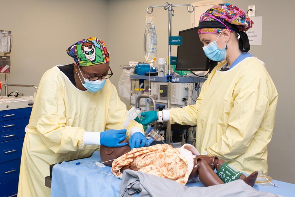 两名英国东北大学的学生穿着外科手术服在病人模拟器上工作