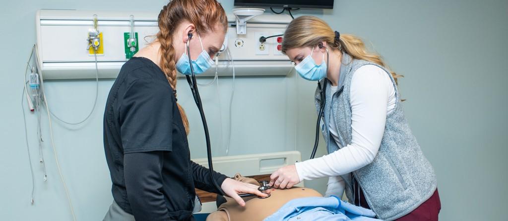 两个护理专业的学生在模拟实验室用假人的听诊器练习听心肺