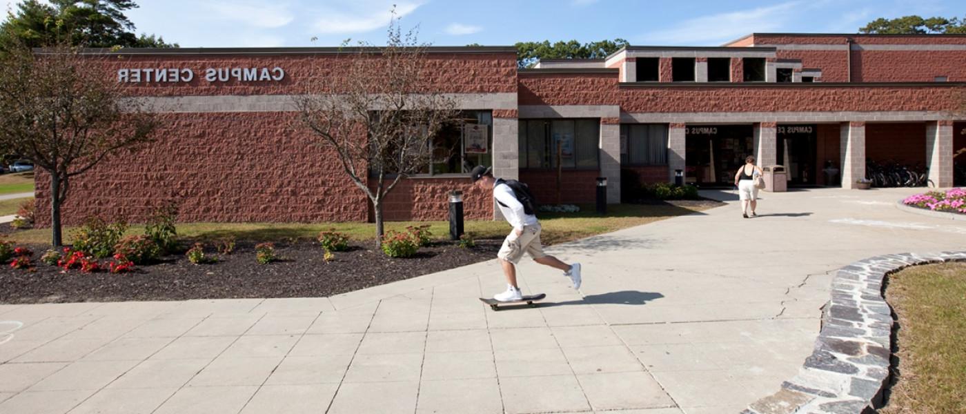 一名学生滑着滑板经过比德福德校区的校园中心